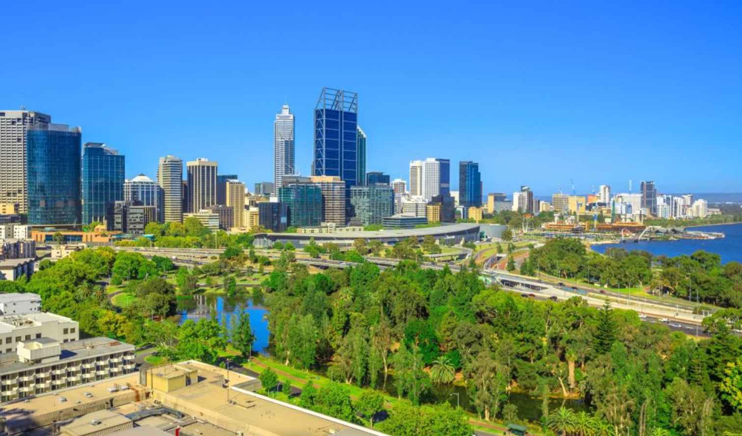 Skyline of Perth, Australia, with skyscrapers and lush greenery in the foreground.
