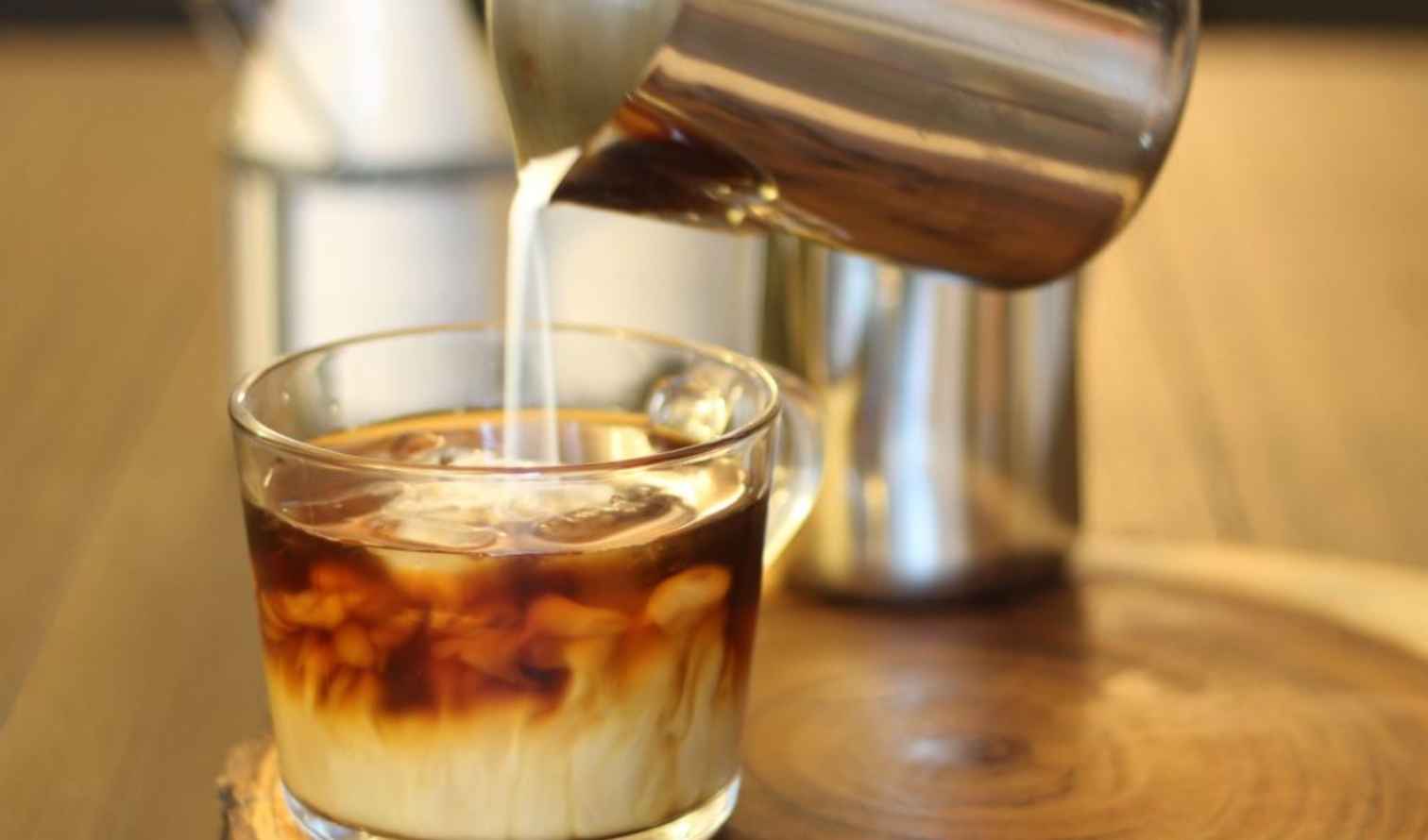 Close-up of iced coffee with milk being poured from a metal jug in Perth