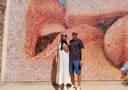 Two people stand in front of the 'El Beso' mural in Barcelona.