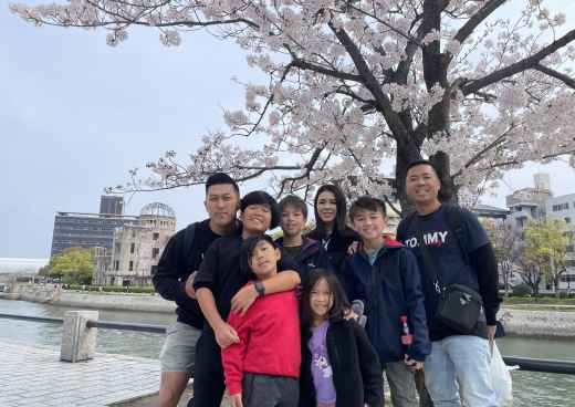 Tourists gathered at Hiroshima's Peace Park with iconic dome in the background.