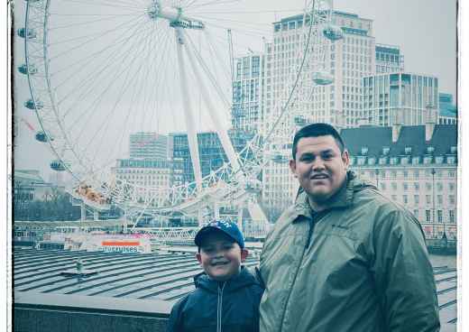 A man and child stand in front of the London Eye.