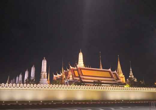 Temple of the Emerald Buddha at night with illuminated spires and wall.