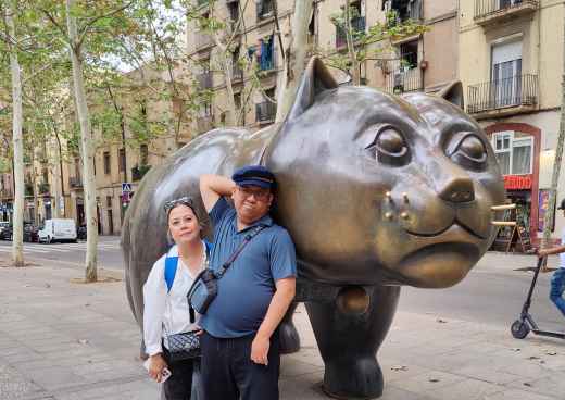 Two people stand beside the sculpture El Gato de Botero in Barcelona.