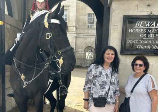 Two women pose near a mounted guard at Horse Guards Parade, London.