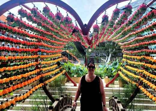 Person beneath decorative flower display with steps and foliage in background.