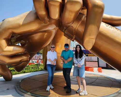 Golden Moments: Striking a Pose Under Giant Hands