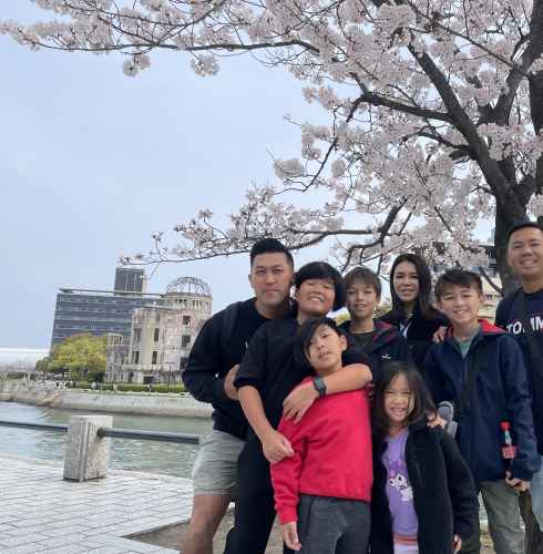 Tourists gathered at Hiroshima's Peace Park with iconic dome in the background.