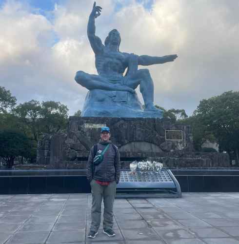 A person stands at the Nagasaki Peace Park, featuring the Peace Statue.