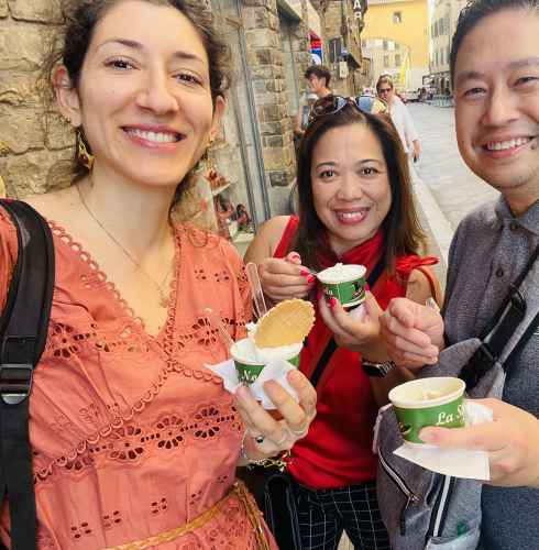 Three people holding gelato cups on a street in Florence, Italy.