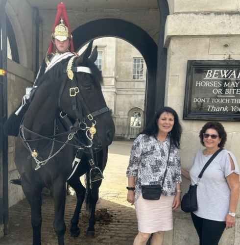 Two women pose near a mounted guard at Horse Guards Parade, London.