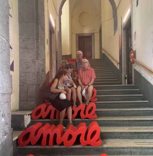 People sitting on red 'amore' benches on a marble staircase.