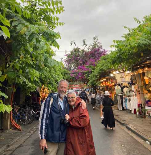 Hoi An street scene with a couple and market vendors.