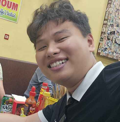 Woman and man posing for a selfie inside a small eatery.