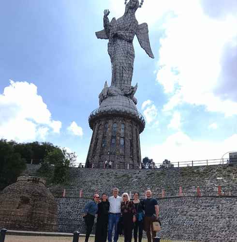 A group of people standing in front of the Virgin of El Panecillo statue, Quito.