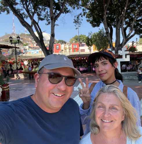 Three people posing at a Mexican square with shops in the background.