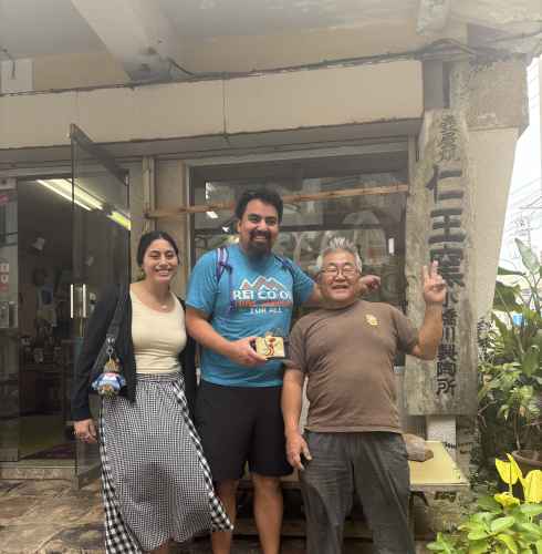 Smiles and peace signs outside a cozy Naha shop.