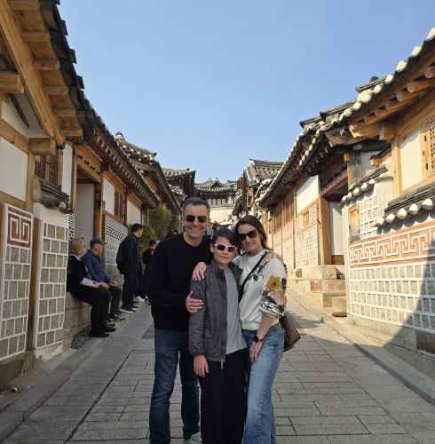 Three people stand on a traditional street in Seoul.
