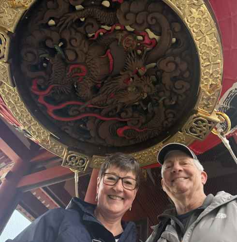Two people standing under a large red lantern at Senso-ji Temple, Tokyo.