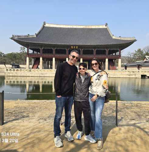 Family posing in front of Gyeonghoeru Pavilion at Gyeongbokgung Palace, Seoul.