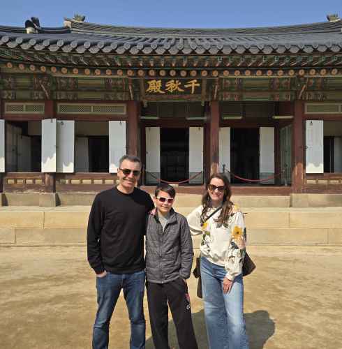 Visitors in casual attire at a historic palace entrance in South Korea.