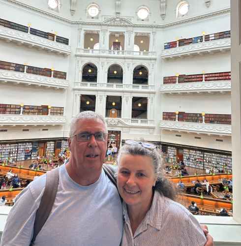 Two people posing inside the State Library of Victoria's reading room.