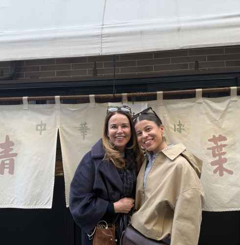 Two people standing in front of a restaurant with Japanese signage.
