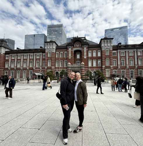 People standing in front of Tokyo Station with skyscrapers in the background.