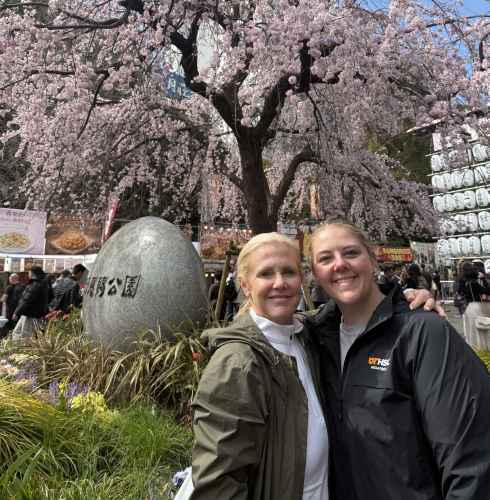 Two people pose in front of a cherry blossom tree in Tokyo.