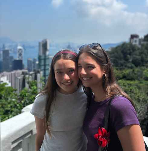 Two friends share a smile with Hong Kong's skyscrapers behind them.