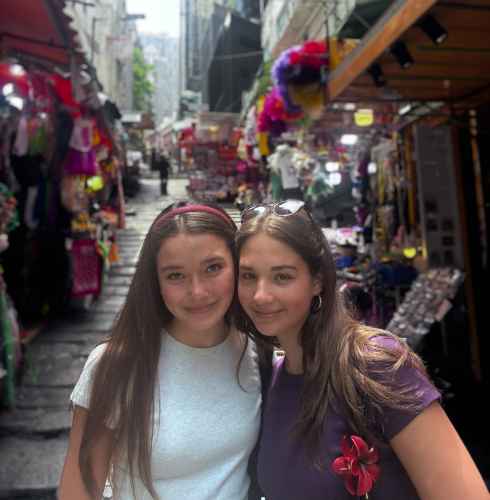 Tourists pausing for a smile amidst Hong Kong's bustling market lanes.