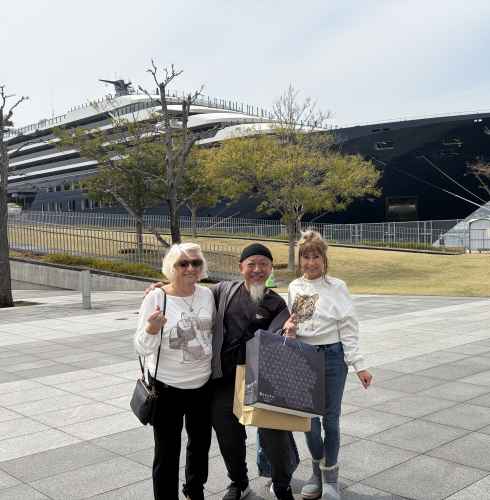 A happy trio poses by an impressive ship in Nagasaki.