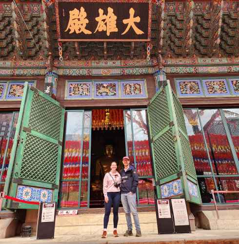 Tourists standing before a temple entrance in vibrant Seoul colors.
