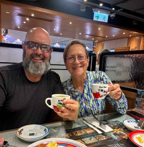 Tourists enjoying a warm cup of tea in a lively Hong Kong diner.