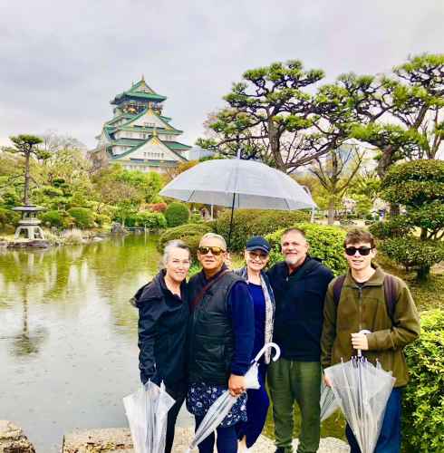 A group enjoys a rainy day stroll in Osaka's gardens.