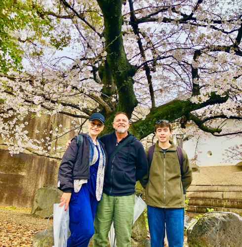 A group smiles beneath blooming cherry blossoms in Osaka.
