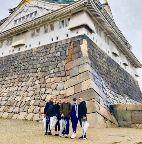 A group stands together under the grandeur of Osaka Castle.