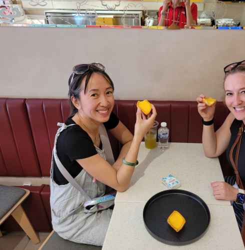 Tourists enjoying local treats in a cozy Singapore eatery.