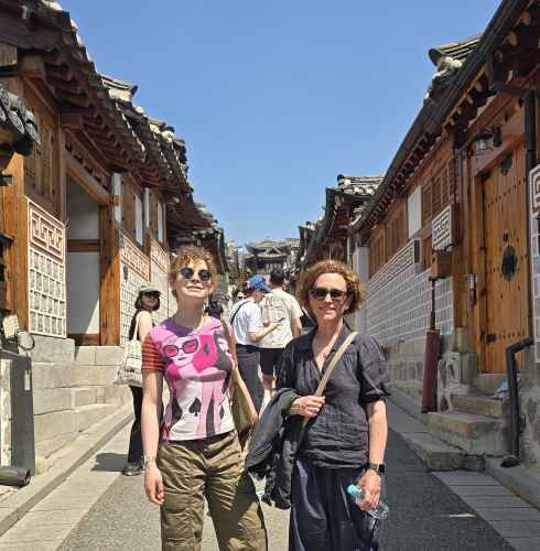 Strolling through Seoul's historic hanok village under a bright blue sky.