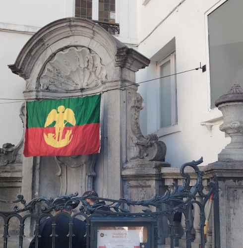 A colorful flag drapes over a historic fountain in Brussels.