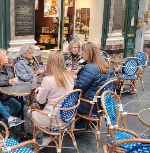 Friends share stories over coffee at a Brussels café.