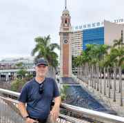 Man standing in front of Tsim Sha Tsui Clock Tower in Hong Kong.