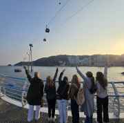 Tourists reaching for the sky as cable cars glide over Busan Bay.