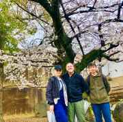 Tourists standing under cherry blossoms in full bloom, smiles all around.