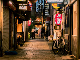 A quiet, early-morning street in Osaka with shuttered market stalls and soft light. A quiet, early-morning street in Osaka with shuttered market stalls and soft light.