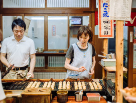 Takoyaki being flipped at a street stall with the chef using metal picks. Takoyaki being flipped at a street stall with the chef using metal picks.