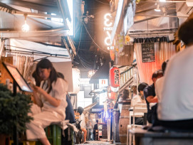 A traveler seated at a modest Osaka eatery, pointing at a handwritten Japanese menu while the chef smiles behind the counter; residential streets and laundry-draped balconies visible through the window. Photo by Satoshi Hirayama on pexels A traveler seated at a modest Osaka eatery, pointing at a handwritten Japanese menu while the chef smiles behind the counter; residential streets and laundry-draped balconies visible through the window. Photo by Satoshi Hirayama on pexels
