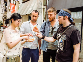 A traveler and local host sharing food on a backstreet. A traveler and local host sharing food on a backstreet.