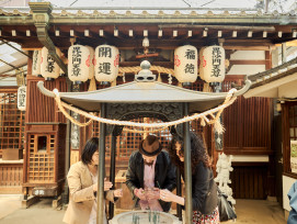 A small group of travelers discovering a tucked-away shrine hidden in a quiet Osaka alley, surrounded by stone lanterns and lush greenery. A small group of travelers discovering a tucked-away shrine hidden in a quiet Osaka alley, surrounded by stone lanterns and lush greenery.