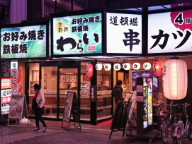 Osaka alleyway with food stalls lit up by warm lanterns, crowds gathering as evening approaches Osaka alleyway with food stalls lit up by warm lanterns, crowds gathering as evening approaches