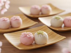 Traditional Japanese sweets designed to match cherry blossom colors arranged on bamboo plates. Traditional Japanese sweets designed to match cherry blossom colors arranged on bamboo plates.